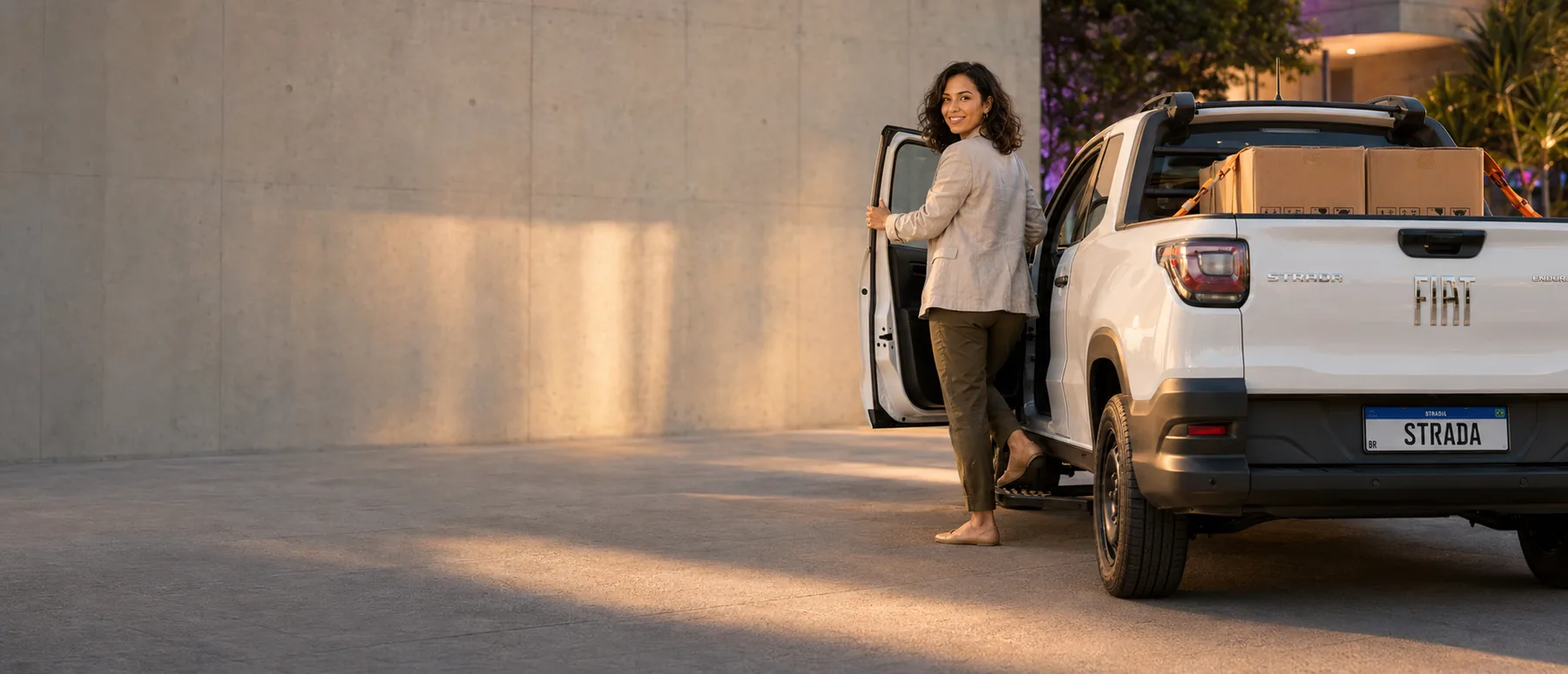 Mulher entrando em uma Fiat Strada ao entardecer